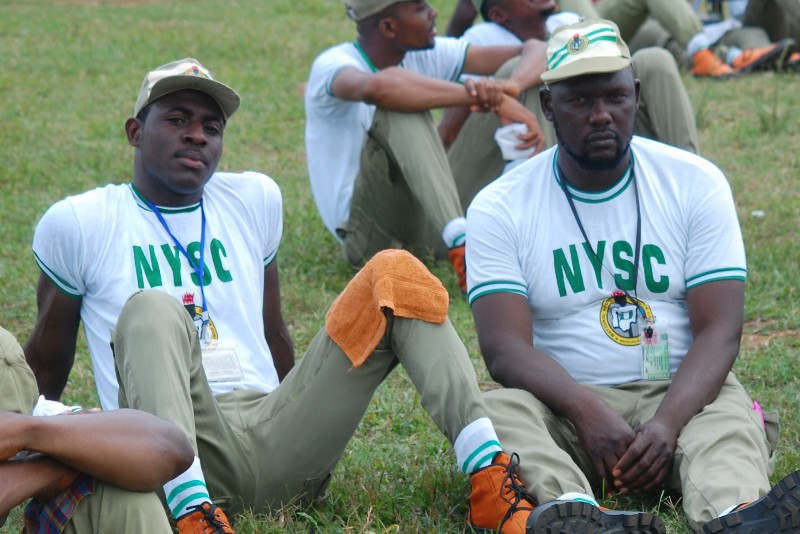 Two nysc friends sitting on the grass enjoying camp