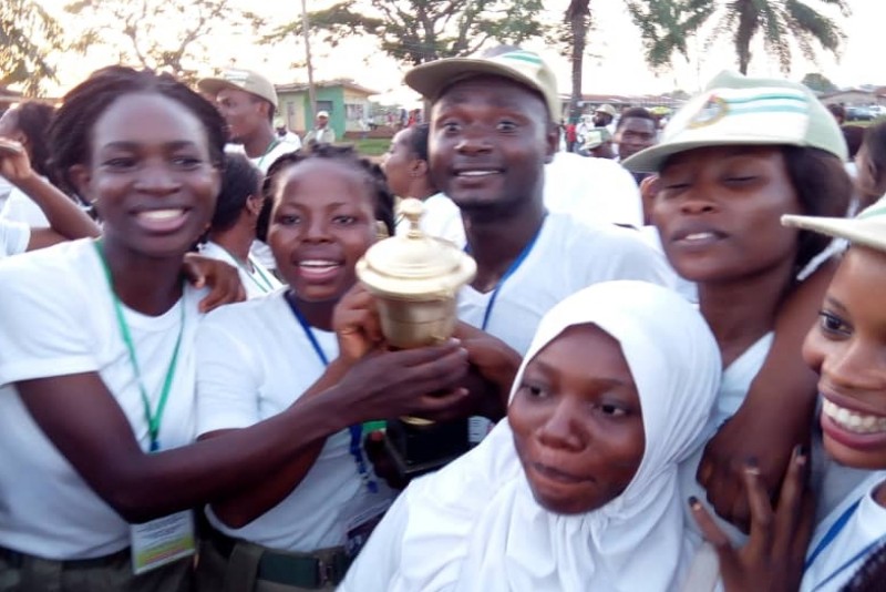 Corps member holding a cup of victory