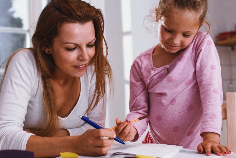 A woman helping her kids with assignment as a tip on how to prepare your child for school resumption